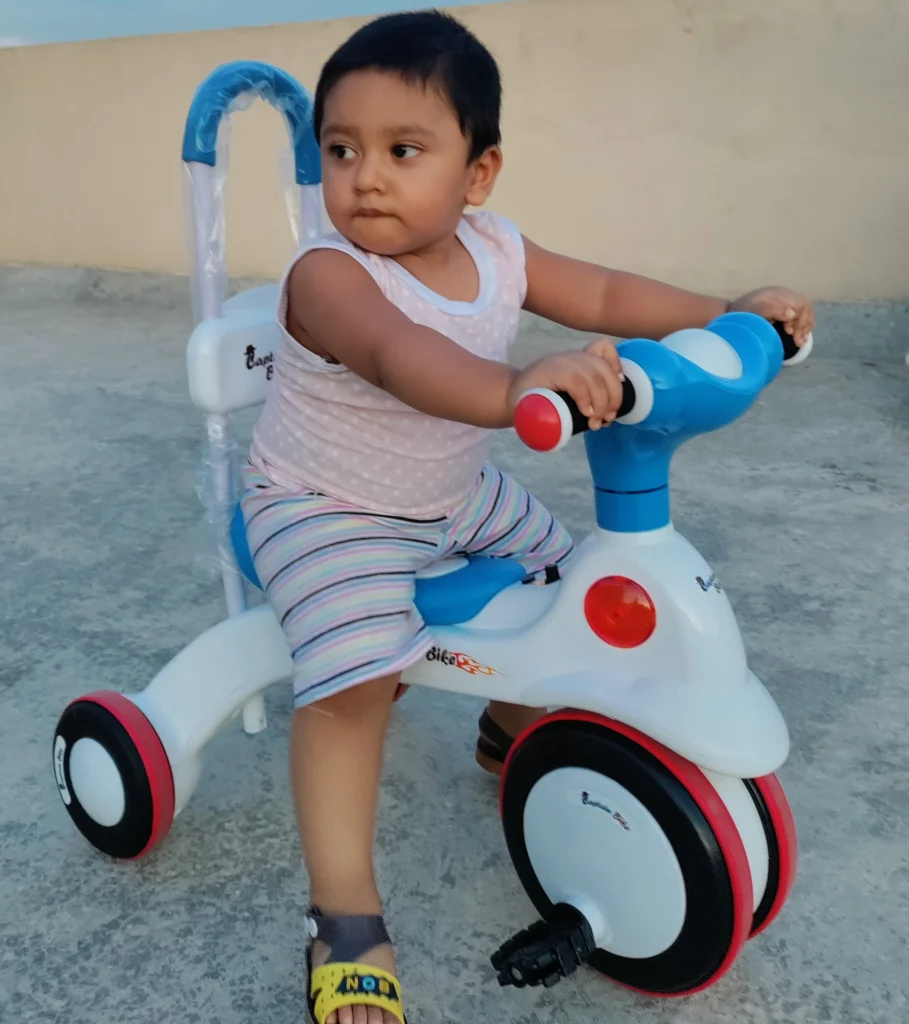 A baby is enjoying a tricycle ride